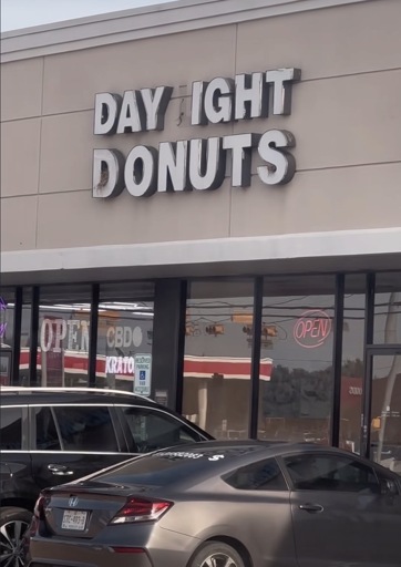 Picture of a storefront sign with a missing letter reading “DAY IGHT DONUTS”